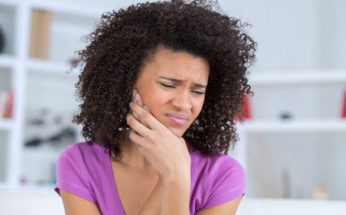 Woman holding her jaw in pain from a dental abscess